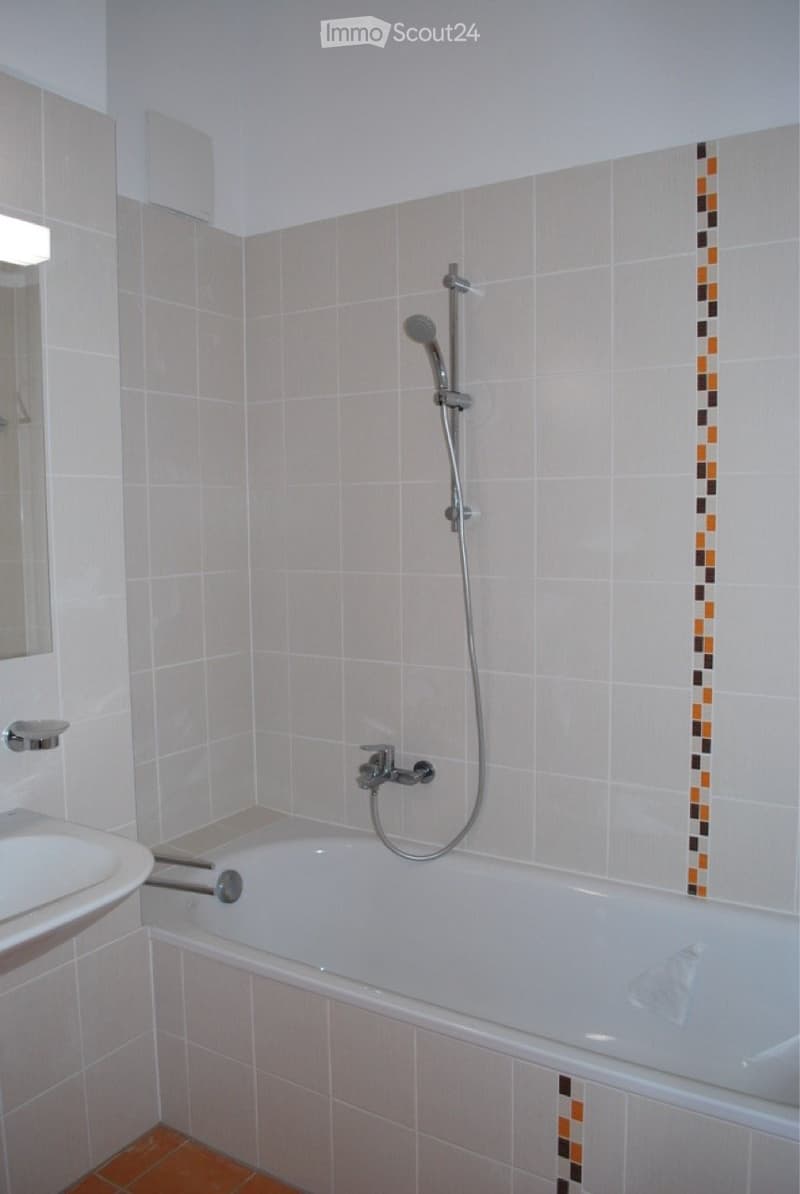 white bathtub, white sink, mirror, white tiles, silver shower head