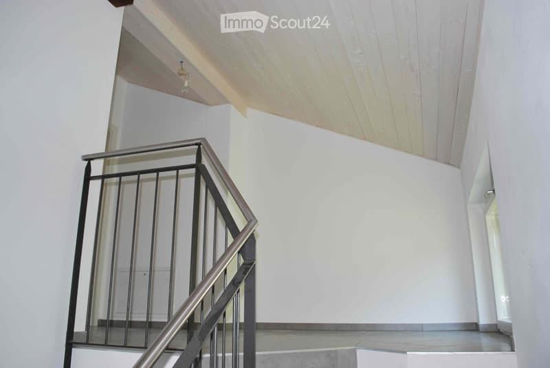 Empty stairs leading to upper floor, white walls, metal railing, slanted ceiling