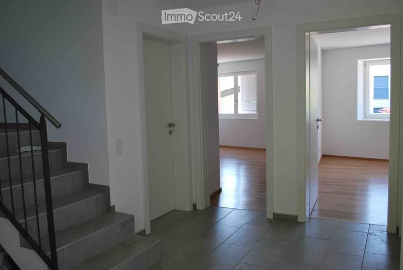 empty hallway, stairs, two doors, light wooden floors