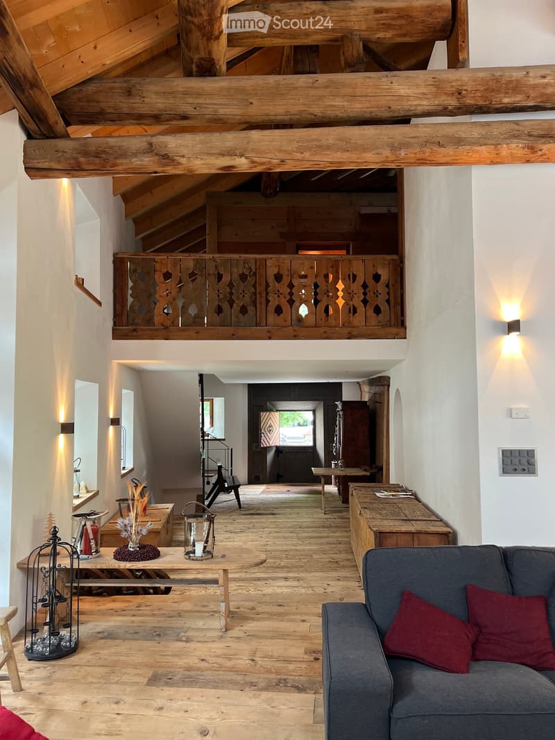 Wooden beams, wooden floor, couch, dining table, lamps, decorative objects, wooden desk, loft with balcony