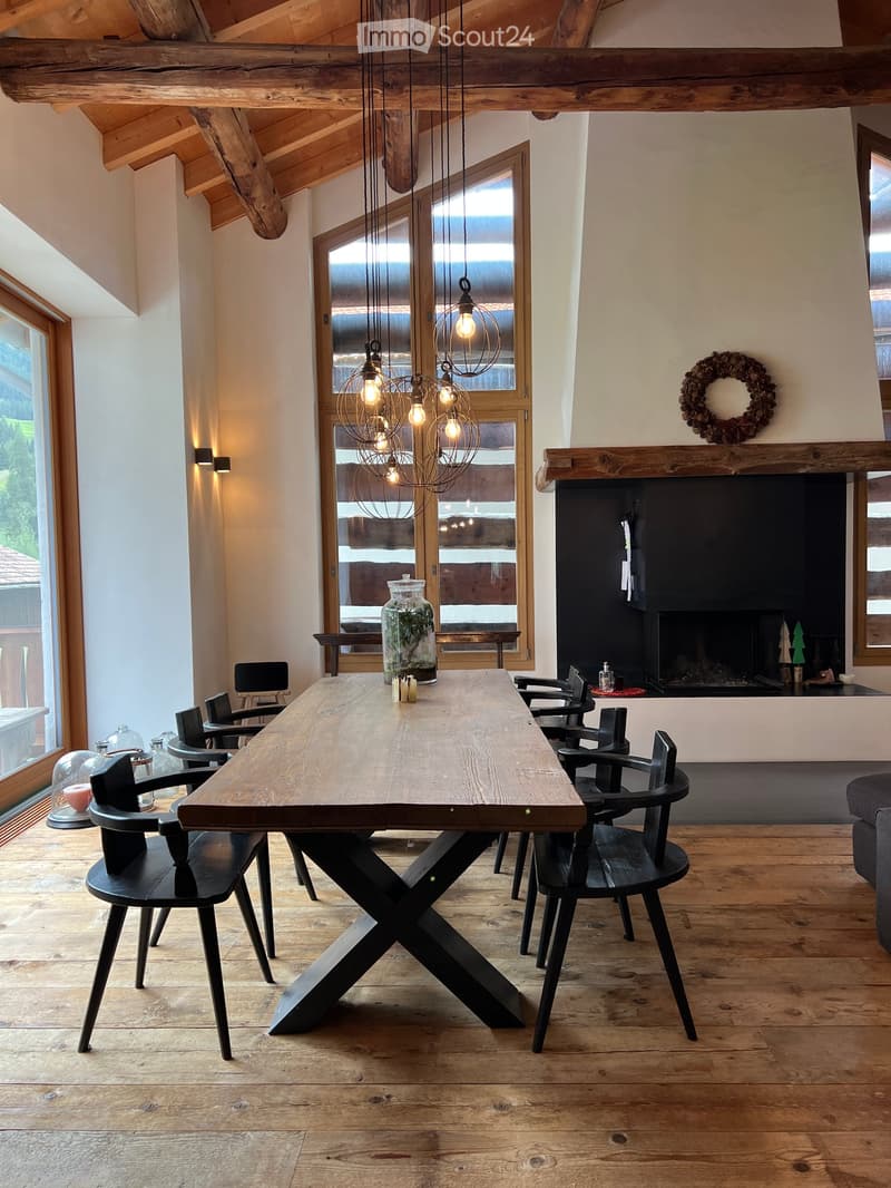 Fireplace, large wooden table, black chairs, chandelier, large windows, glass decorations