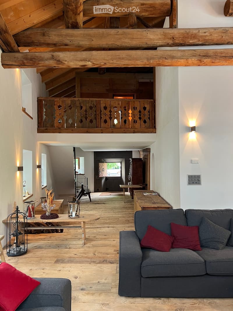 Open floor plan, wooden floor, two couches, wooden table, raised wooden gallery