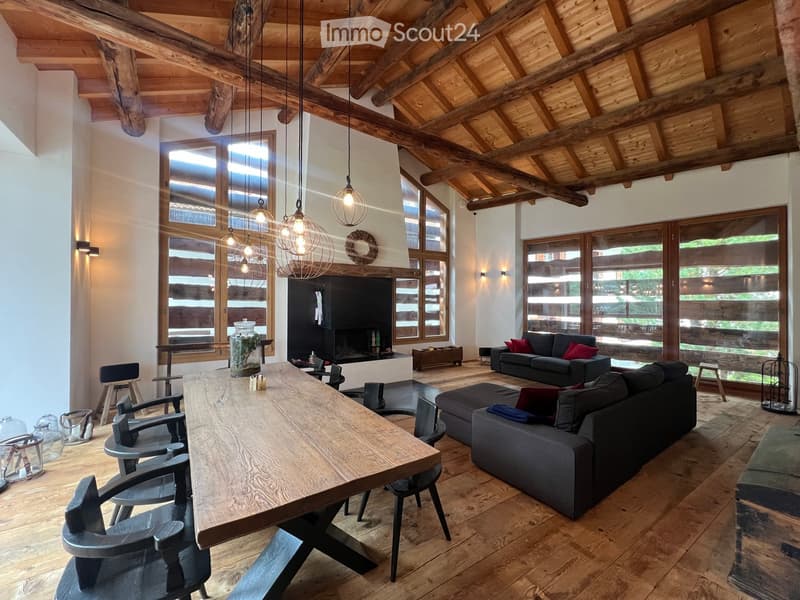 a wooden table, large glass windows, chandeliers, large sofa, fireplace, wooden floor