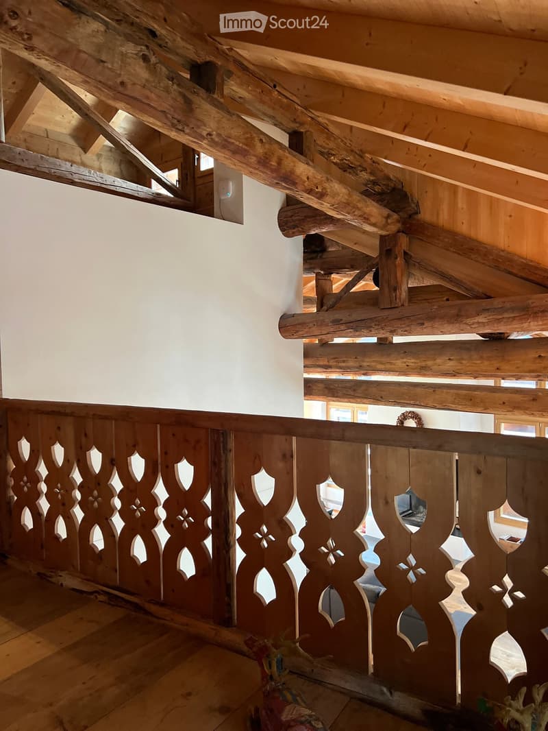 wooden ceiling beams, carved wooden railings, white walls, wooden floor