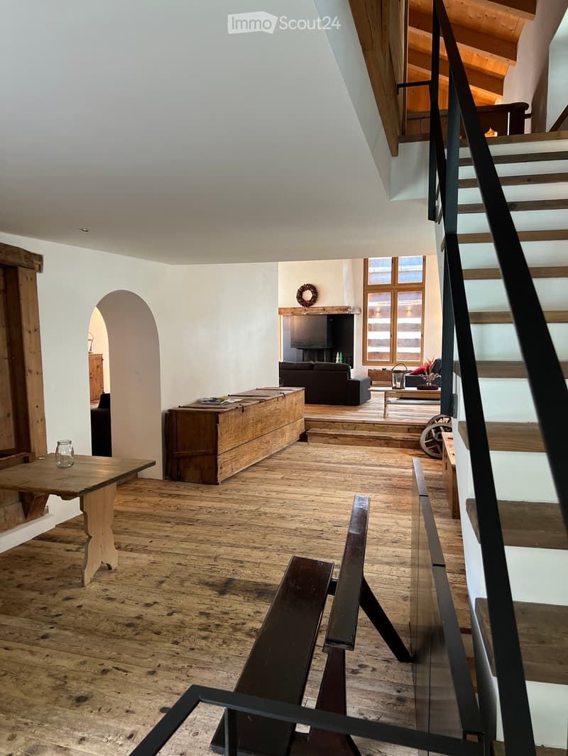 wooden floor, wooden table, black railing, arch entrance, TV, sofa, wooden bench