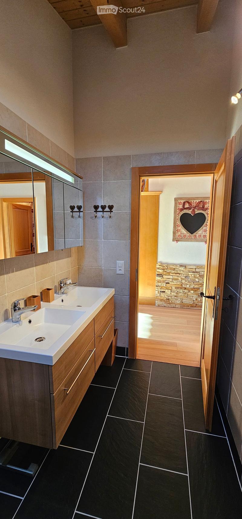 bathroom with double sink, mirror, wooden cabinet, open door