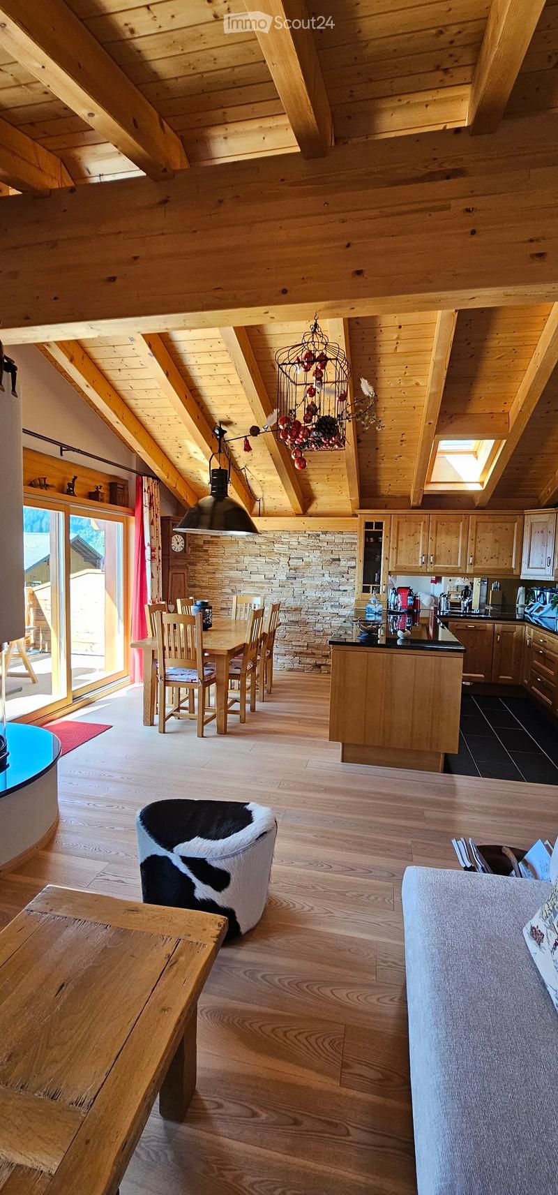 Open concept living and dining room, wooden ceiling beams, dining table, chandelier, brick wall, kitchen island