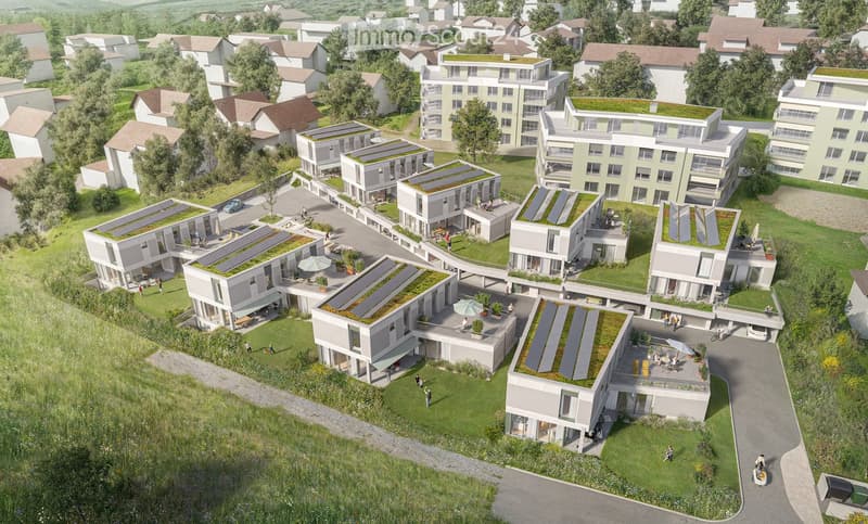Building. A modern residential complex with multiple buildings featuring green roofs, solar panels, and outdoor seating areas. The area includes pathways, greenery, and parking spaces.