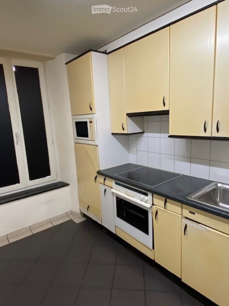 yellow cabinets, black countertop, stainless steel sink, black stovetop, white oven
