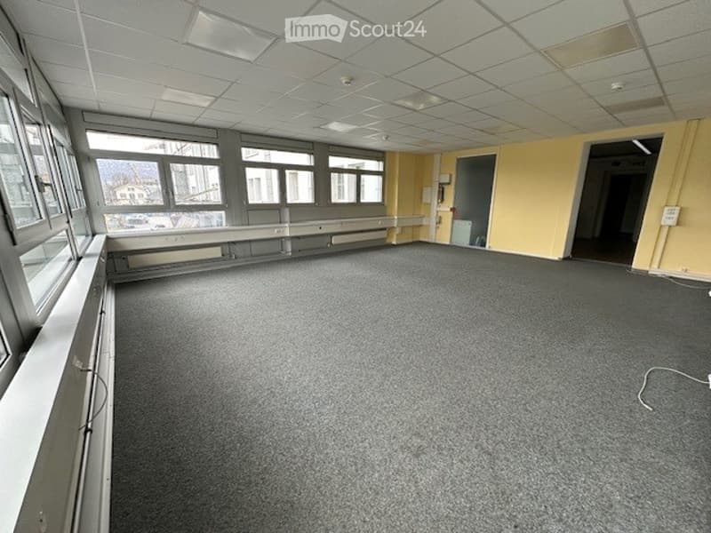 A carpeted room with yellow walls and large windows.