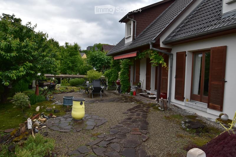stone pathway, chairs, table, greenery, large house in the background