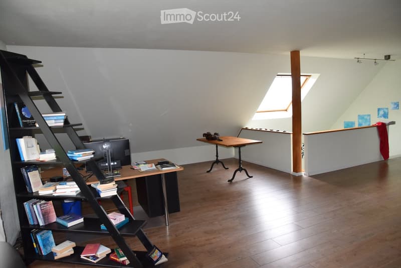 Empty room with hardwood floors, shelves, desks, and a ceiling with a skylight