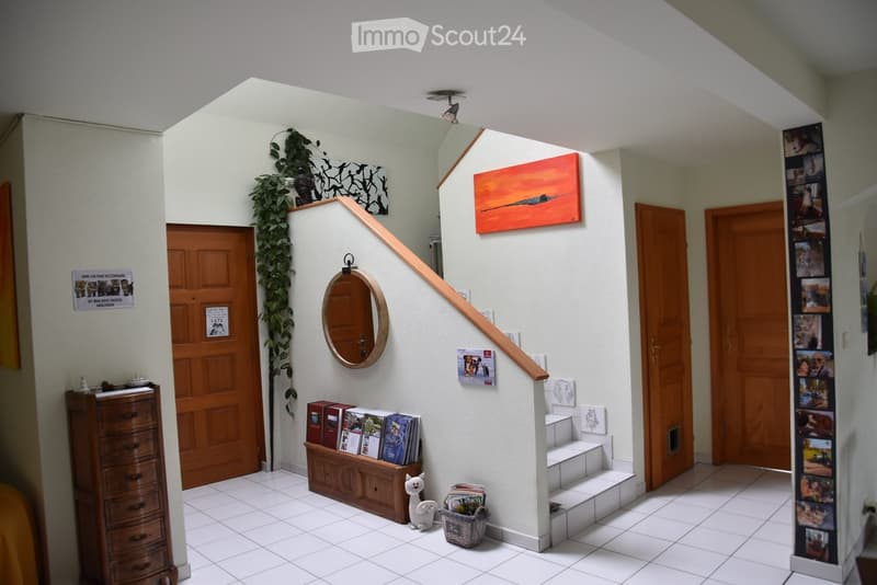 tiled floor, wooden doors, small wooden cabinet, wooden stair railing, mounted picture frame, mirror, plants, baskets