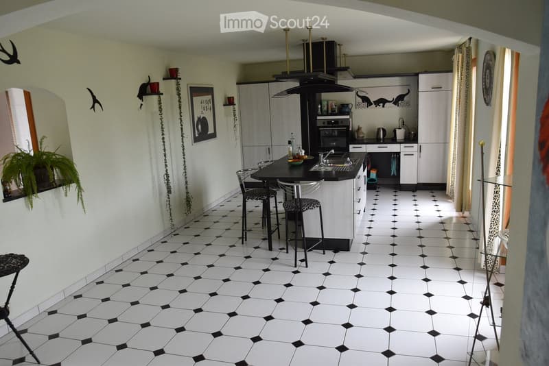 kitchen, black and white floor, island with two stools, large windows, shelves with decor