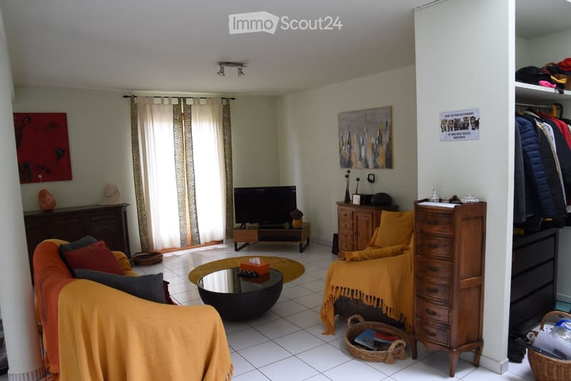 a living room with sofa, center table, cabinet, basket and curtained windows