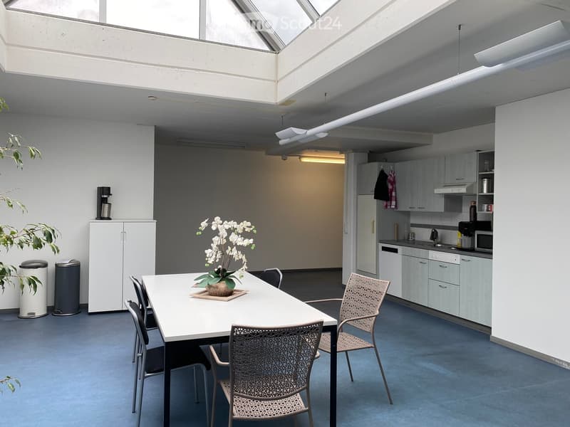 dining area with table, chairs, flowers, modern kitchen with appliances, cabinets, sink, and trash bins
