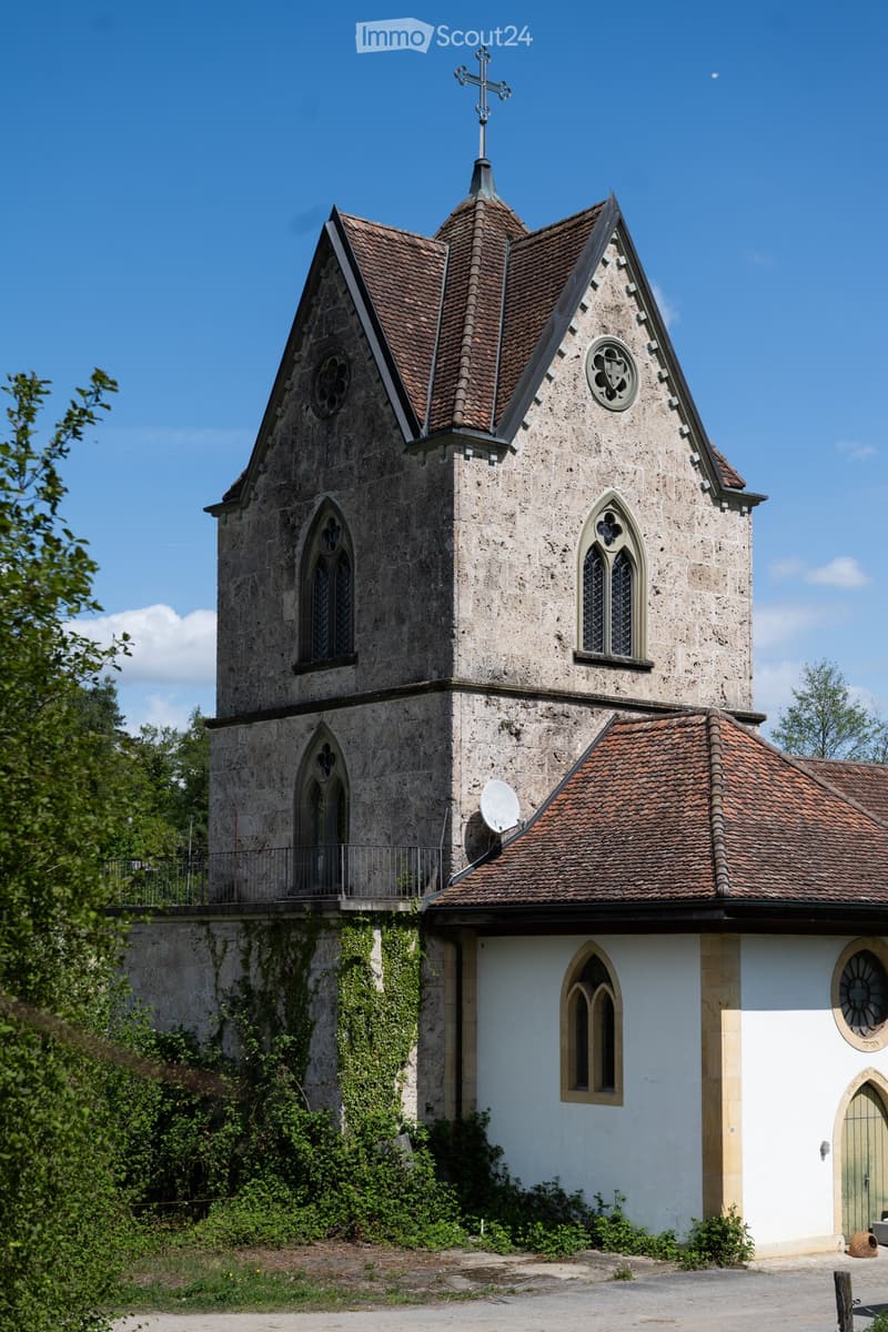 old stone building, cross on top, arched windows, brown roof, satellite dish, ivy on the wall