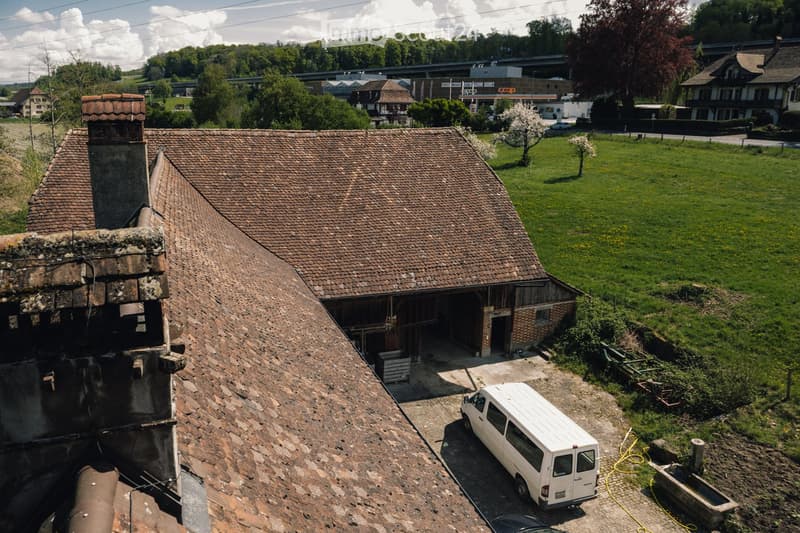 Old house with red roof, chimney, white van parked in front, brick walls, large open garage