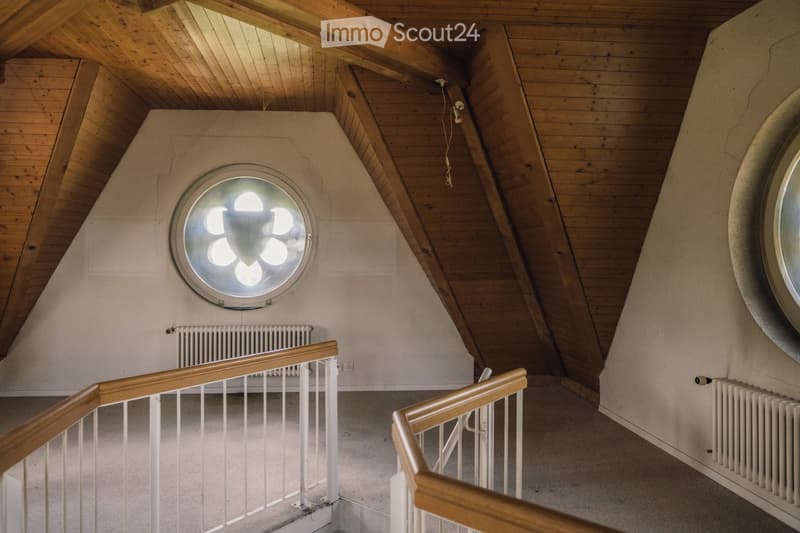 wooden ceiling, white walls, round window, wooden handrails, radiators