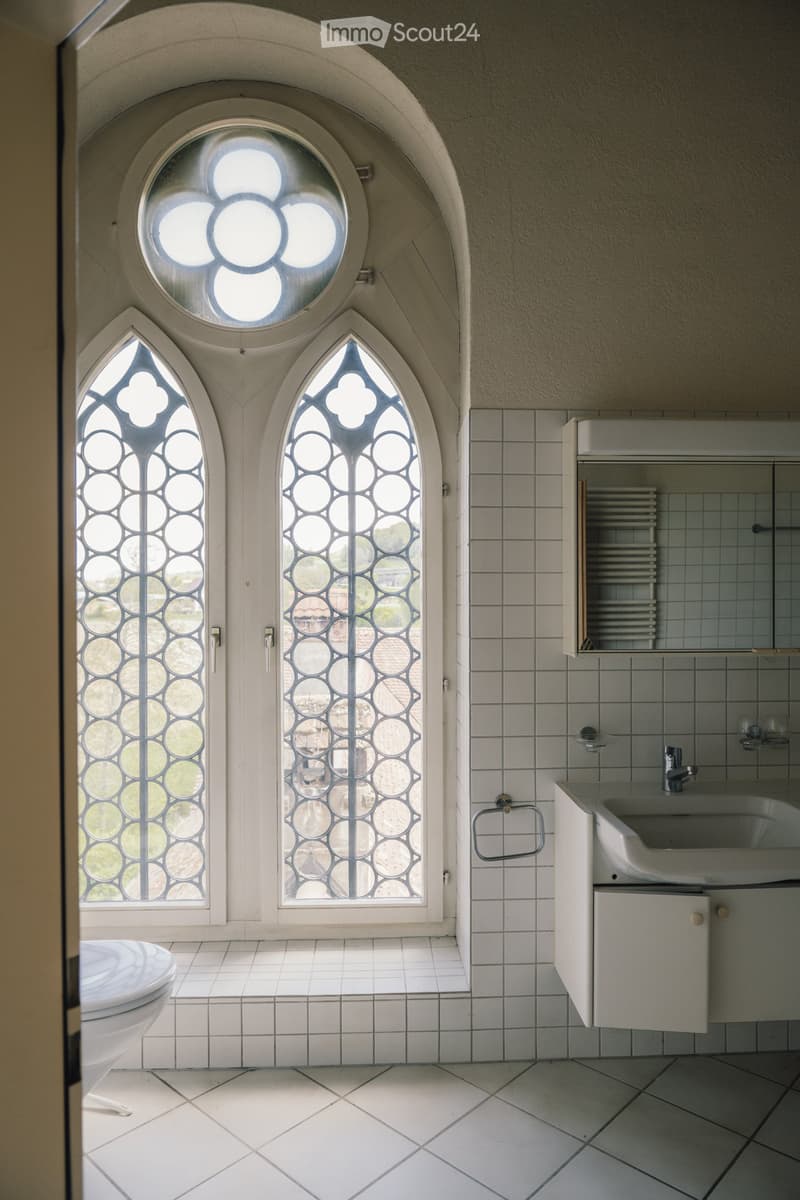white tiled floor, white tiled walls, white sink, white toilet, arched window, mirror
