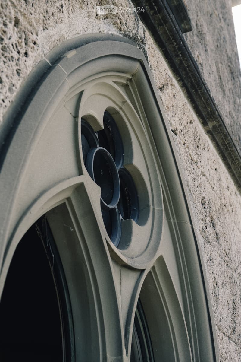 arched window with decorative stonework, black window frame, concrete wall