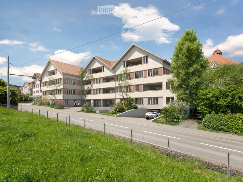 large multi-storey building, beige color, many windows, some balconies, trees, parking area, road