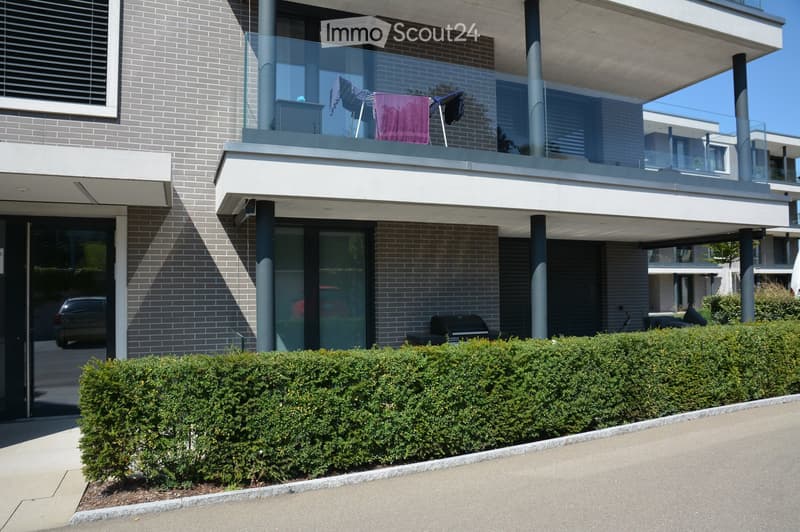 modern building, grey brick, glass door, balcony with glass railing, outdoor grill