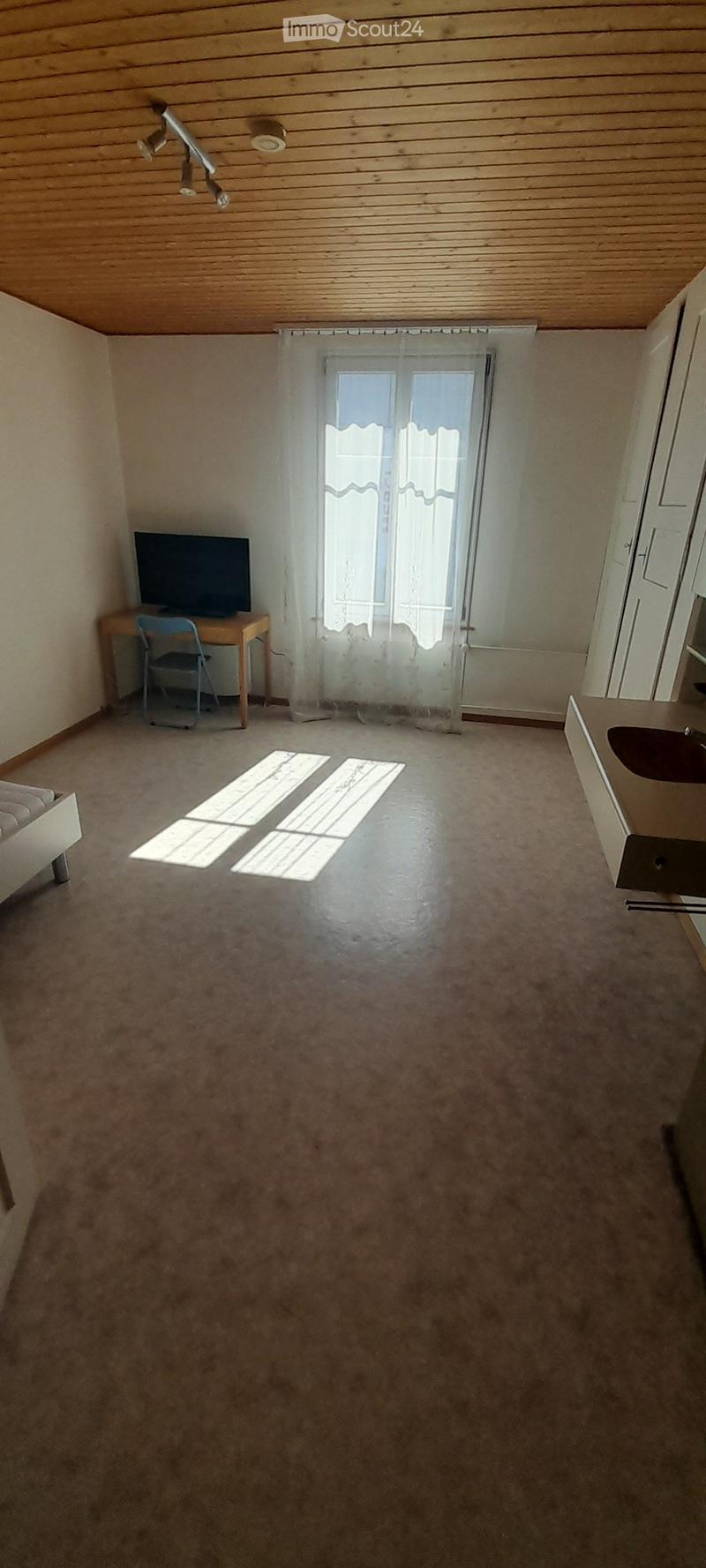 Bedroom with wooden ceiling, white walls, large window, desk, and TV