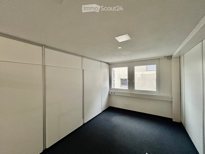 an empty room with white walls, a black floor, and a window