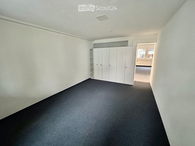 Empty room with white walls, black floor, and built-in white cabinets.