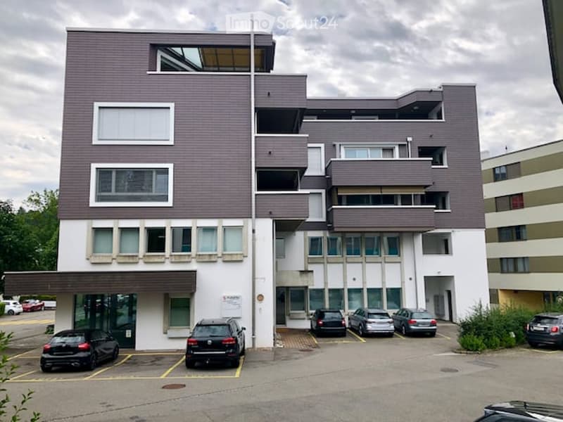 residential building, 3 levels, brown and white facade, multiple windows, parking area with several cars