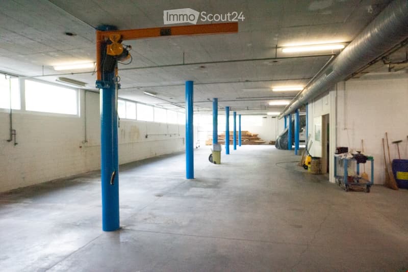 spacious open room with metal beams and pillars, fluorescent ceiling lights, concrete floor, small equipment and tools on the side