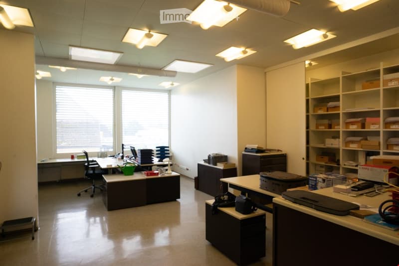 Modern office layout with large windows, built-in storage, desks, and seating
