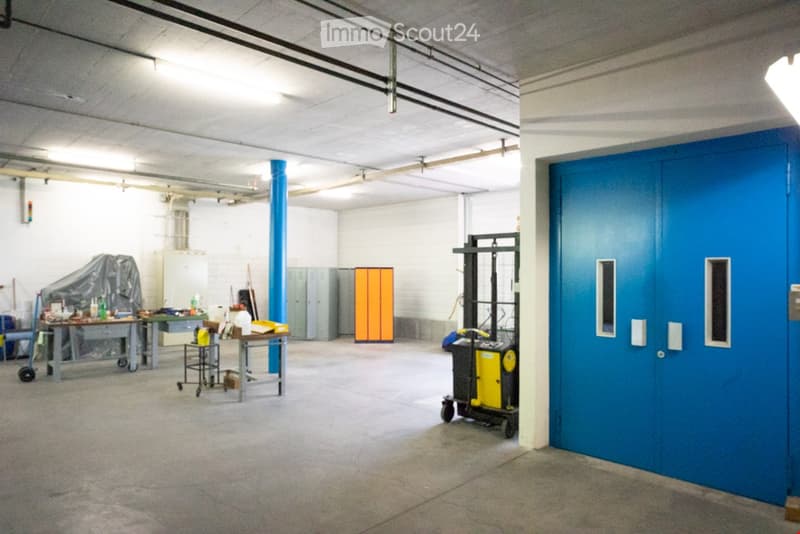 Open garage with industrial cabinets, blue double doors, tables with tools, forklift, and various equipment.