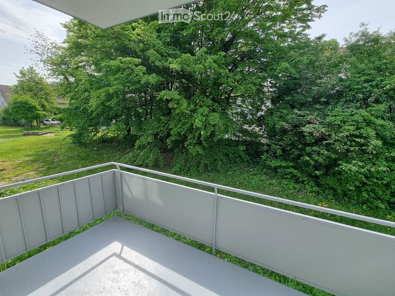 Balcony / Terrace. A balcony with a white railing and a view of a grassy area with trees.