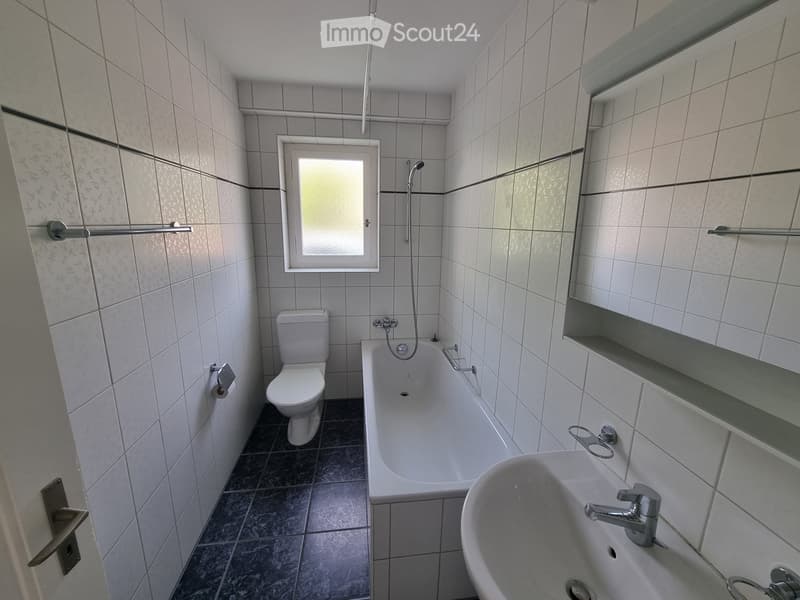 Bathroom. Bathroom with white tiles, black floor, toilet, bathtub, shower head, sink, mirror, and soap dish.