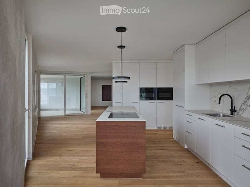 open space, wooden floors, island with cooktop, white cabinetry, black faucet, modern pendant lights