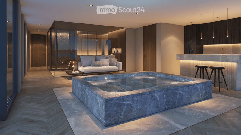 Living area with an indoor swimming pool, large sofa, wooden floors, and an open view to the kitchen