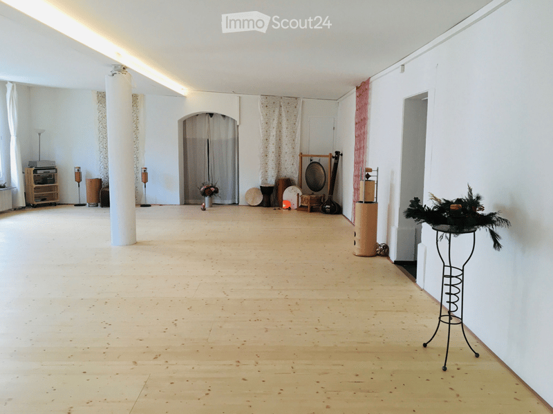 Empty room with wooden floor, white walls, and various musical instruments and decorations placed around the room.