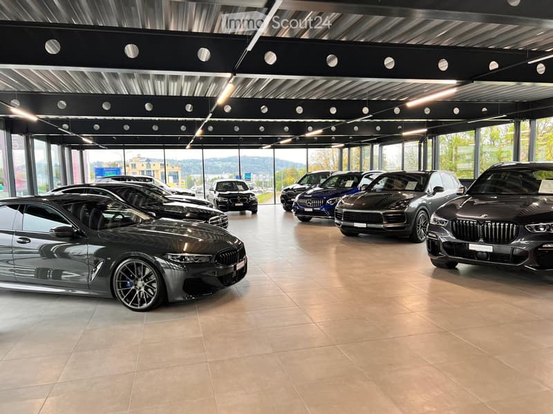 Showroom with cars on display, spacious, tiled flooring, glass walls, ceiling lighting