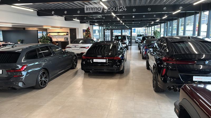 interior of a car showroom with various cars parked, including BMWs, with polished floors and glass walls