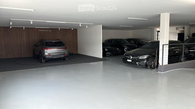 Underground garage, several cars parked, track lighting, pillar, wooden partition wall