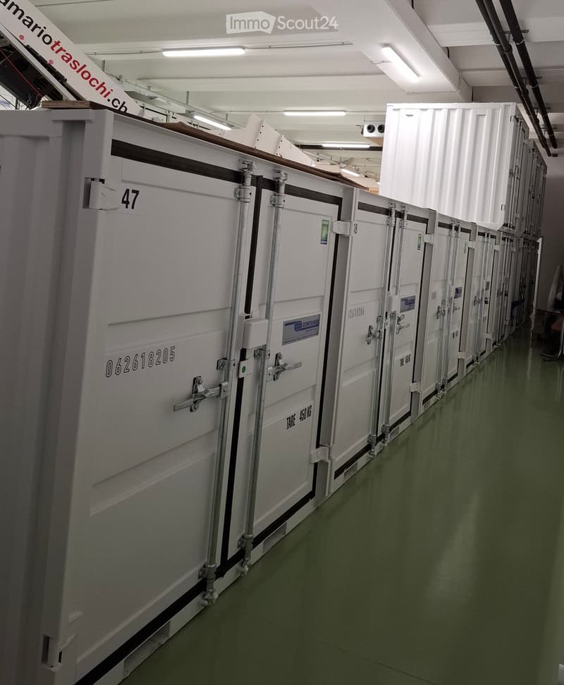 Row of white storage containers with numbers and labels, green floor, metal ceiling, white walls