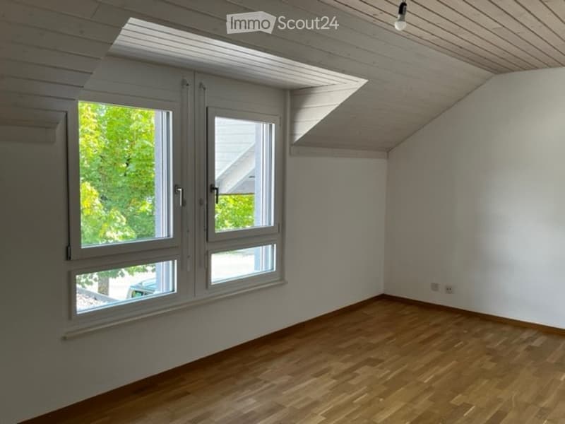 empty room, wooden floor, large windows, slanted ceiling, wall mounted power outlets