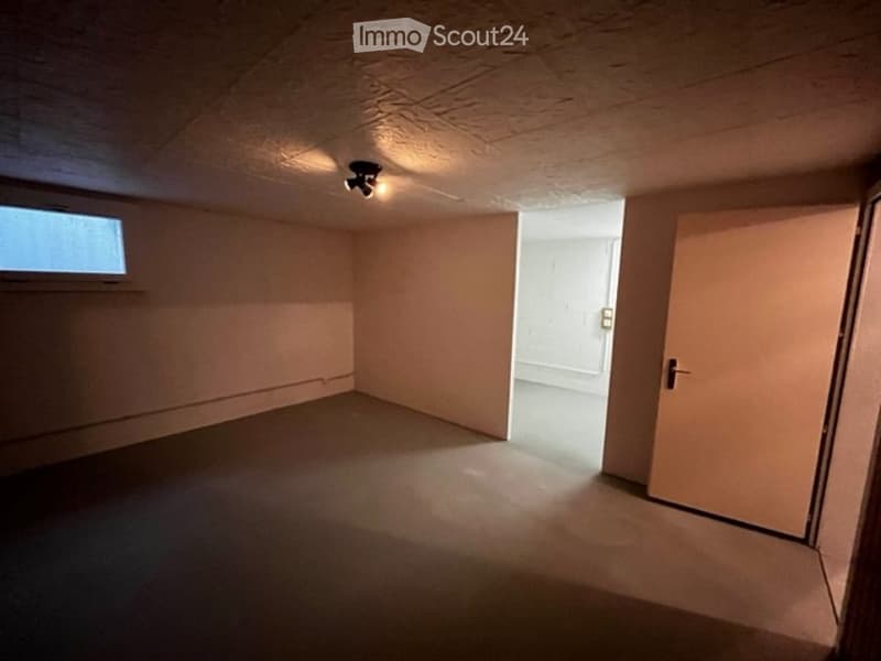 empty room, beige walls, brown floor, small window, door