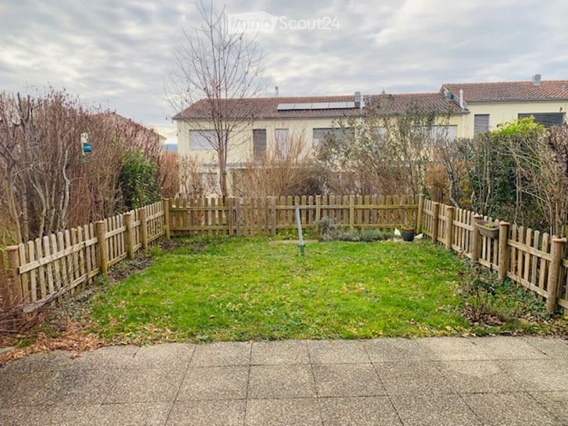 green grass, wooden fence, paved walkway, building in the background