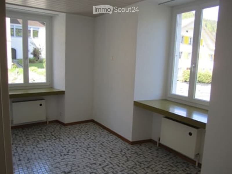 Empty room with windows, two radiators, tiled floor