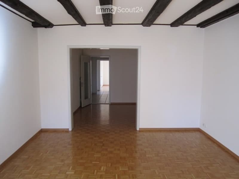 wooden floor, white walls, open doorways, wooden beams on ceiling