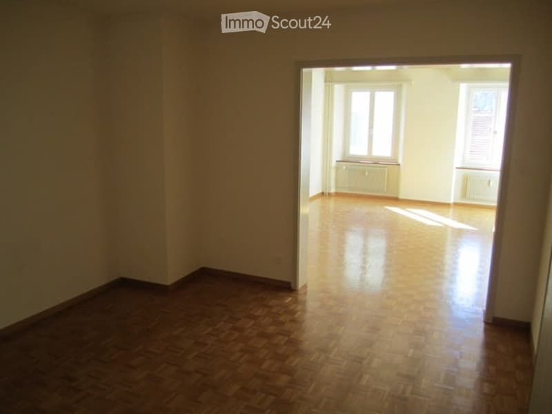 room with parquet floor, white walls, two windows, two white radiators, door