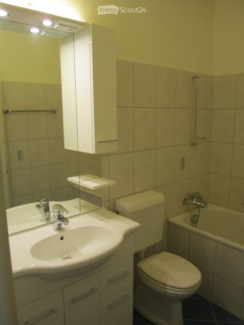 White bathroom with sink, toilet, and bathtub. Light yellow walls.